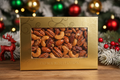 Generate a 1lb box of mixed glazed nuts (Pecans, Almonds, and Cashews), in a festive setting. The box should be gold with a window, we should focus on the nuts, not the people in the setting. The nuts should look freshly glazed and delicious